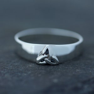 May include: A silver ring with a Celtic knot design featuring three black stones.