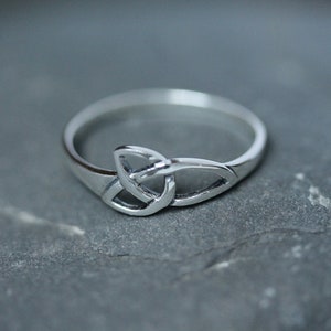 May include: A silver Celtic knot ring with a simple design.