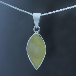 May include: A silver pendant with a teardrop-shaped yellow stone.
