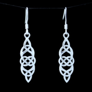 Könnte beinhalten: Silberne Ohrhänger mit einem keltischen Knotendesign. Die Ohrringe sind silberfarben und haben eine Tropfenform.