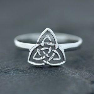 May include: A silver ring with a Celtic knot design. The knot is in the shape of a triangle.