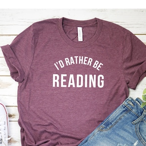 May include: A maroon t-shirt with the text "I'd rather be reading" in white lettering.