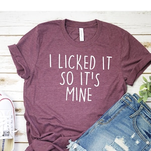 May include: A maroon t-shirt with the text "I licked it so it's mine" in white lettering.