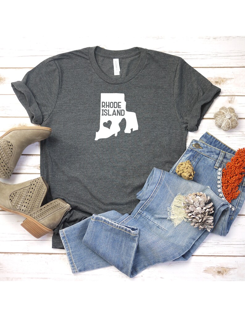 K&ouml;nnte beinhalten: Ein dunkelgraues T-Shirt mit einer wei&szlig;en Umrandung des Bundesstaates Rhode Island und dem Text "Rhode Island" mit einem kleinen Herzen innerhalb der Bundesstaatenumrandung.