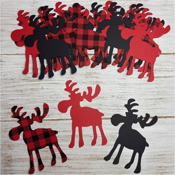 May include: A collection of moose cutouts in red, black, and red and black buffalo plaid patterns. The moose shapes are scattered across a light wood-grain surface, with some overlapping. The cutouts vary in size and are suitable for crafting or decoration.
