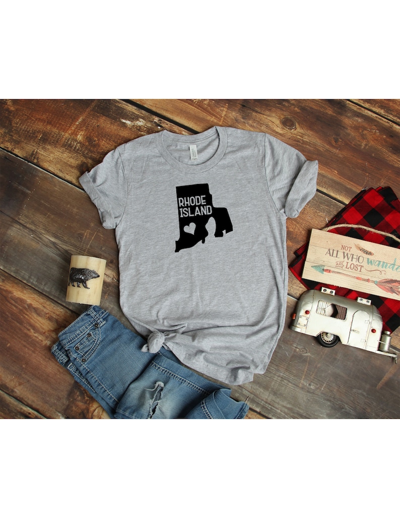 K&ouml;nnte beinhalten: Graues T-Shirt mit einer schwarzen Umrandung des Bundesstaates Rhode Island und dem Text "Rhode Island" mit einem kleinen Herzen innerhalb der Bundesstaatenumrandung.