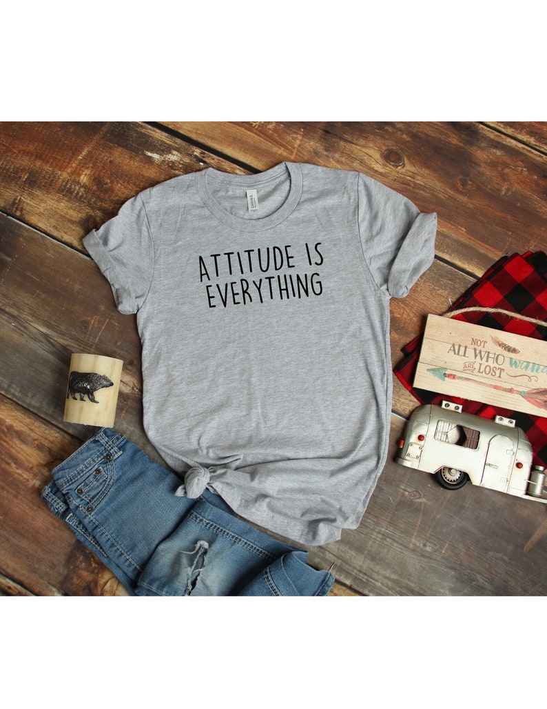 May include: Gray t-shirt with the text "ATTITUDE IS EVERYTHING" printed in black.