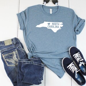 May include: A blue t-shirt with a white outline of the state of North Carolina and the text "I love North Carolina" with a heart symbol.