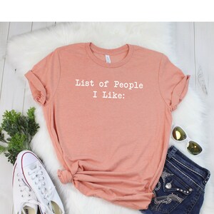 May include: A peach-colored t-shirt with the text "List of People I Like:" printed in white.