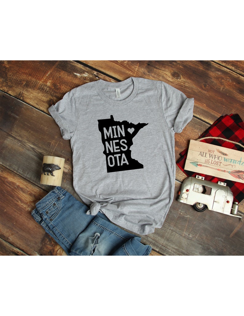 May include: Gray t-shirt with a black outline of the state of Minnesota and the text "MINNESOTA" with a heart in place of the "O".