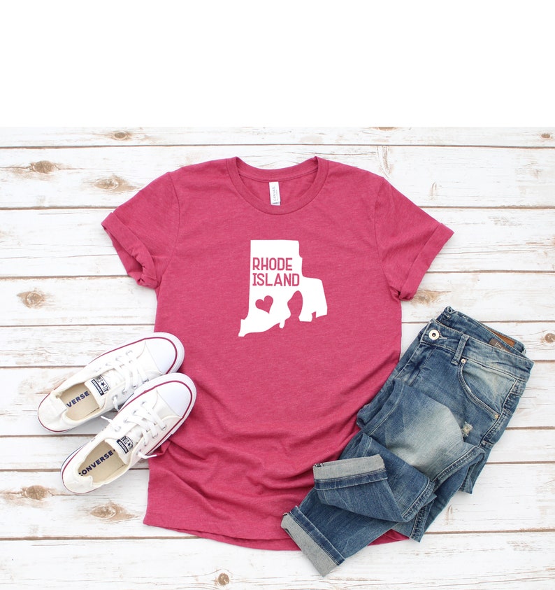 K&ouml;nnte beinhalten: Ein pinkfarbenes T-Shirt mit einer wei&szlig;en Umrandung des Bundesstaates Rhode Island und dem Text "Rhode Island" mit einem kleinen Herzen innerhalb der Bundesstaatenumrandung.