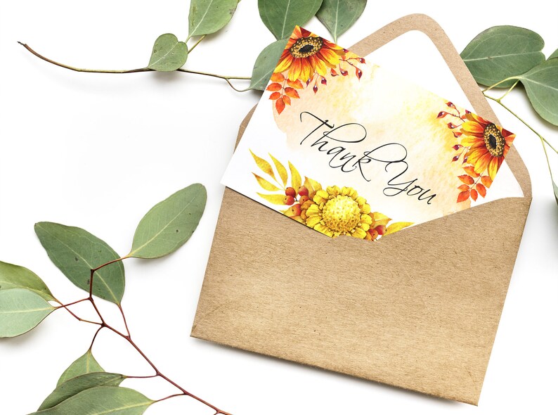 May include: A white card with a watercolor design of sunflowers and leaves in shades of yellow, orange, and red. The card has the text "Thank You" written in black calligraphy.