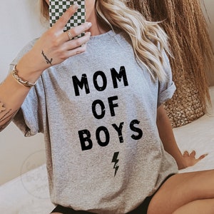 May include: Gray t-shirt with the text "MOM OF BOYS" in black with a lightning bolt underneath.