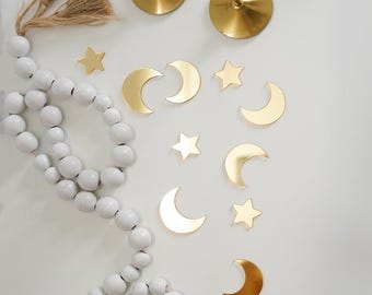 May include: A white beaded garland with gold crescent moons and stars scattered around it. Two gold candle holders with white candles are in the top left corner of the image.