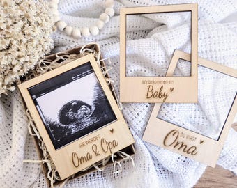 Könnte beinhalten: Holzrahmen mit dem Text "Wir bekommen ein Baby" und "Du wirst Oma" auf weißem Hintergrund. Die Rahmen sind für Ultraschallbilder gedacht.