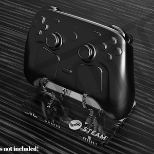 May include: A black Steam Deck controller on a clear stand, with the Steam logo and text. The controller has buttons, triggers, and joysticks. The background is a textured, dark surface. "Controllers not included!" is written at the bottom.