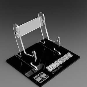 May include: A clear acrylic stand with a black base for displaying a Game & Watch:  Bassmate computer. The base has the text "GAME & WATCH" and "BASSMATE COMPUTER" printed on it.