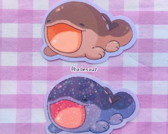 May include: Two cartoon frog stickers with open mouths. The first frog is brown with a light orange mouth. The second frog is blue with a sparkly texture and a light pink mouth. Both frogs have a light blue outline.