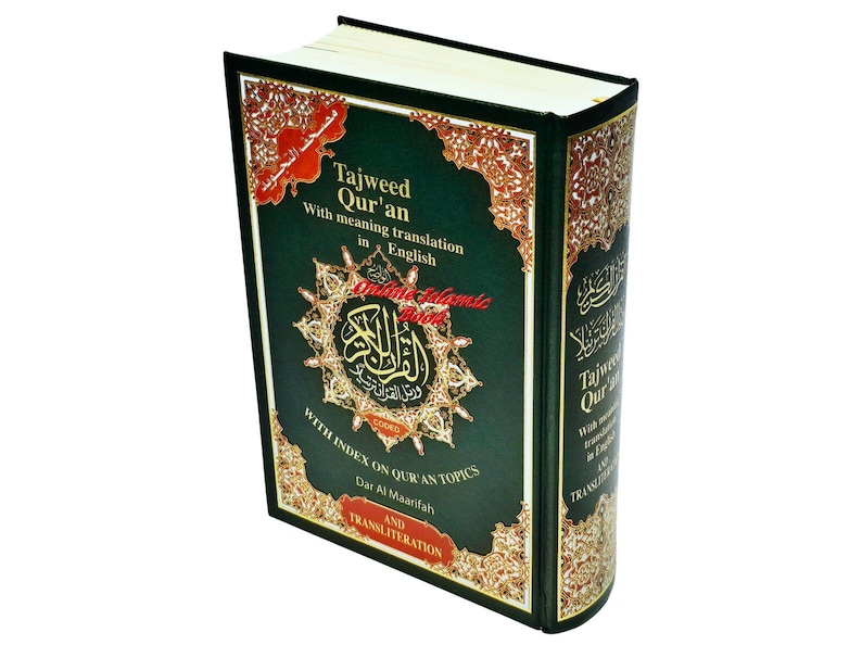 May include: A hardcover book titled "Tajweed Qur'an" with English translation. The cover is dark green with gold and red decorative elements. The book's spine also features text. The book is angled slightly, showcasing its cover and spine.