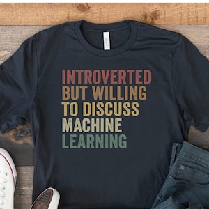 May include: A black t-shirt with the text "Introverted but willing to discuss machine learning" in a vintage style font.