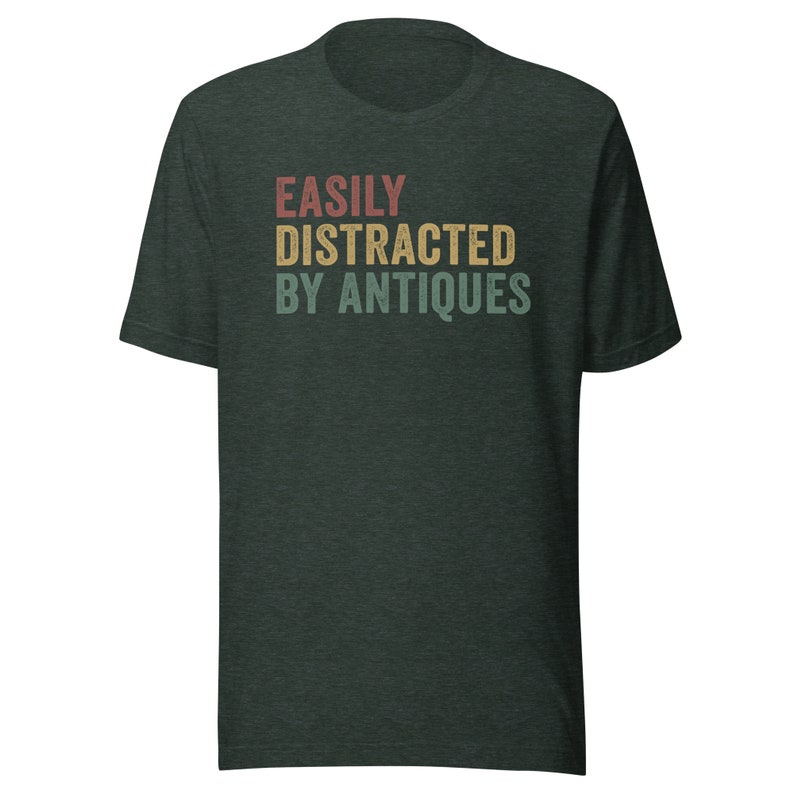 May include: A dark green t-shirt with the text "EASILY DISTRACTED BY ANTIQUES" in a vintage style font with red, yellow, and blue colors.