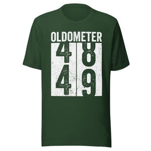 May include: Dark green t-shirt with the word "OLDOMETER" above the numbers 48 and 49 in a white, distressed font. The shirt is a short-sleeved crew neck.