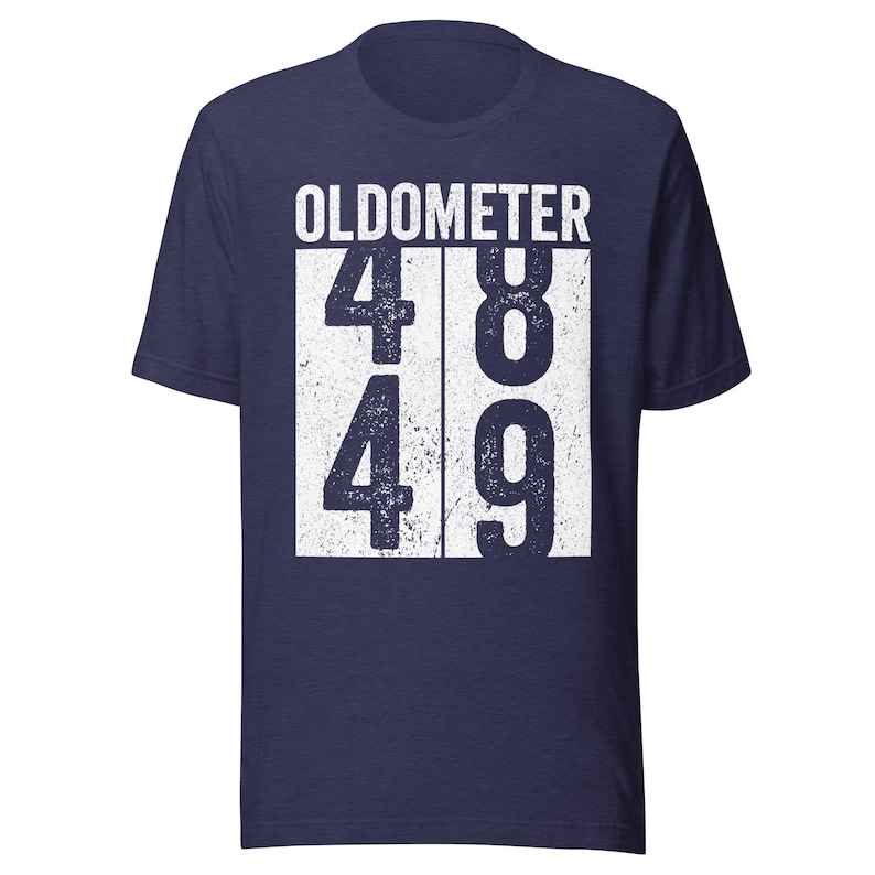 May include: Navy blue t-shirt with the word "OLDOMETER" above the numbers 48 and 49 in a white, distressed font. The shirt is a short-sleeved crew neck.