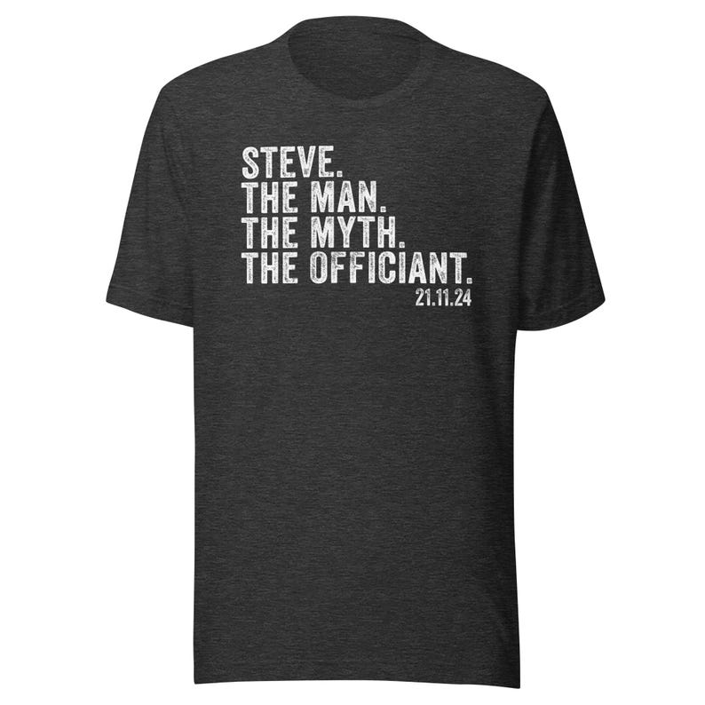 May include: Dark heather grey t-shirt with white text that reads "STEVE. THE MAN. THE MYTH. THE OFFICIANT. 21.11.24"