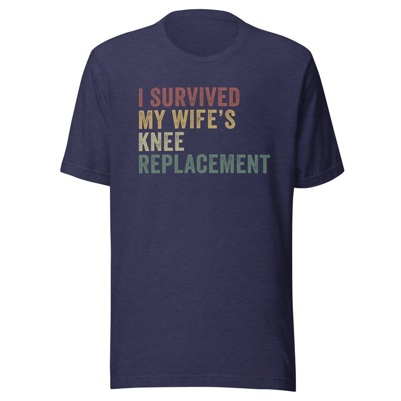 May include: Navy blue t-shirt with a vintage-style graphic that reads "I Survived My Wife's Knee Replacement".