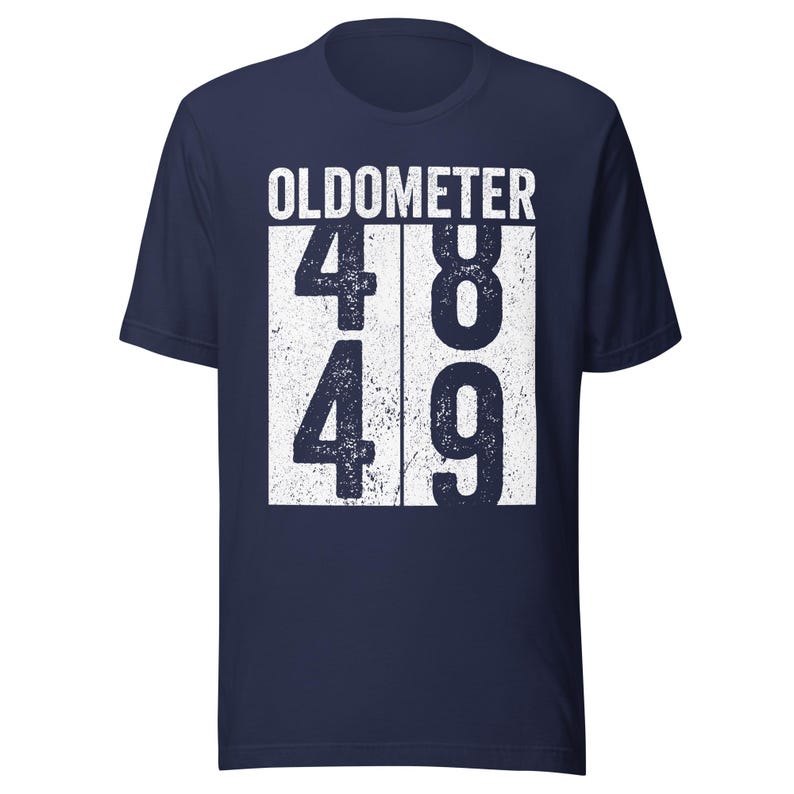 May include: Navy blue t-shirt with the word "OLDOMETER" printed in white. Below the word "OLDOMETER" are the numbers 48 and 49 in a white box. The shirt is a short-sleeved crew neck.