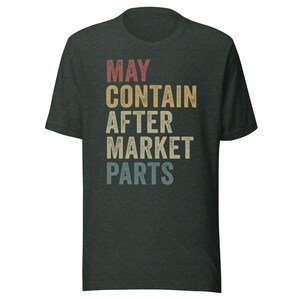 May include: A dark green t-shirt with the text "MAY CONTAIN AFTER MARKET PARTS" in a vintage style font with a rainbow color gradient.