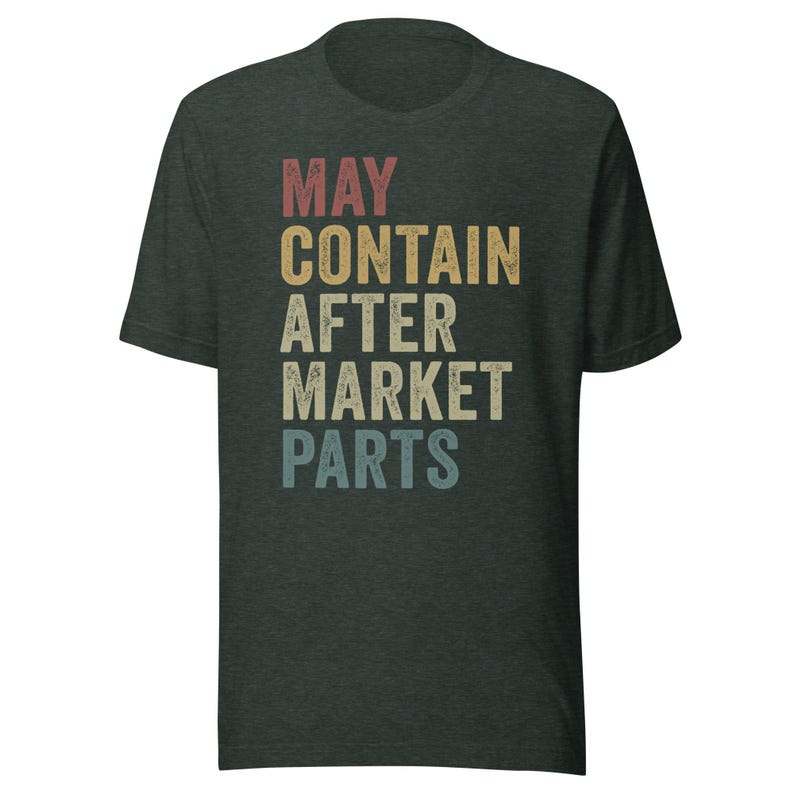 May include: A dark green t-shirt with the text "MAY CONTAIN AFTER MARKET PARTS" in a vintage style font with a rainbow color gradient.