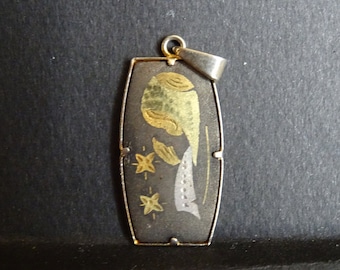 May include: A silver pendant with a black rectangular base and a gold and silver design of a fish with stars.