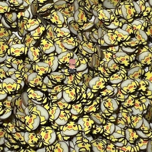 May include: A large quantity of yellow and orange chick-shaped resin embellishments. The chicks are outlined in black and have a white egg shape behind them.