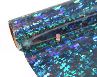 May include: A roll of iridescent holographic vinyl with a blue, green, and purple color scheme. The vinyl is covered in small, randomly-shaped, iridescent pieces.