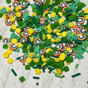 May include: A variety of colorful sprinkles for baking and decorating. The sprinkles include green shamrocks, yellow circles, green and yellow striped sticks, and rainbow-colored half-circles.