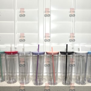 May include: Nine clear plastic tumblers with lids and straws. The straws are in various colors: green, red, purple, pink, black, and blue. The tumblers are all the same size and shape.