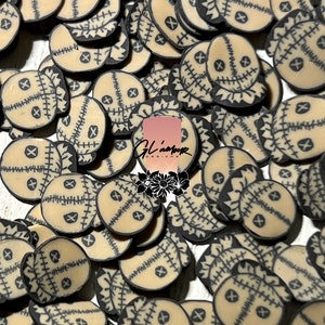 May include: A large pile of beige and black stitched fabric doll heads with stitched X eyes. The doll heads are approximately 1 inch in diameter.