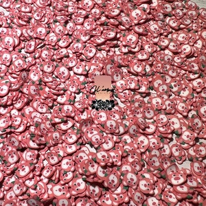 May include: A large pile of pink and white bear face sprinkles. The bears have small green leaves on their heads.