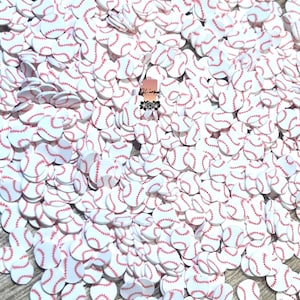 May include: A large pile of white and red baseball-themed confetti. The confetti is in the shape of baseballs with red stitching.