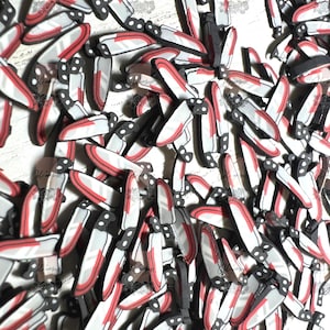 May include: A large pile of red and white plastic knives. The knives are all the same size and shape, and they are arranged in a random pattern.