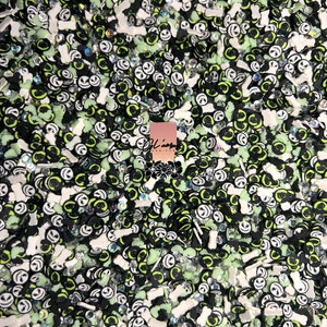 May include: A close-up of a variety of Halloween-themed sprinkles. The sprinkles are in the shape of bones, ghosts, and Jack Skellington's face. The sprinkles are in a variety of colors, including black, white, green, and glow-in-the-dark.