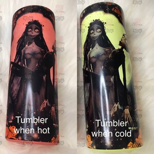 May include: Two images of a stainless steel tumbler with a color-changing design. The tumbler features a graphic of a bride and groom from the movie "The Nightmare Before Christmas". The text "Tumbler when hot" is on the left image and "Tumbler when cold" is on the right image.