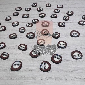 May include: A collection of 30 round, brown resin flatback cabochons with a white face and a black and white illustration of a creepy doll face.