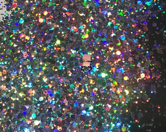 Könnte beinhalten: Nahaufnahme von schimmerndem Glitter in verschiedenen Größen und Formen. Der Glitter ist eine Mischung aus Silber, Blau, Grün und Lila.