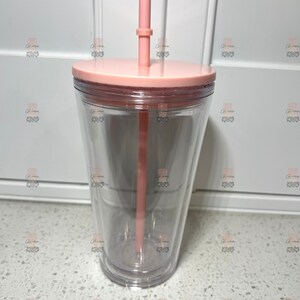 Puede incluir: Un vaso transparente de doble pared con tapa y pajita de color rosa claro. El vaso tiene un dise&ntilde;o c&oacute;nico y est&aacute; hecho de pl&aacute;stico transparente. La pajita es recta y tiene un peque&ntilde;o anillo cerca de la parte superior. La tapa es plana y encaja perfectamente en el vaso.