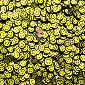 May include: A collection of yellow smiley face polymer clay slices with black edges and pink accents. The slices are round and feature a smiling face with arrows and a starburst design.