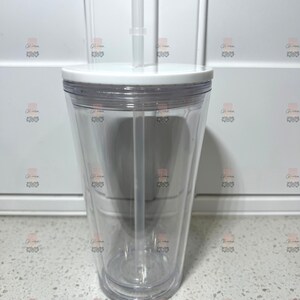 Puede incluir: Un vaso transparente de doble pared con tapa blanca y pajita transparente. El vaso est&aacute; vac&iacute;o, mostrando su dise&ntilde;o transparente. La pajita es recta y encaja en un agujero de la tapa. El vaso est&aacute; dise&ntilde;ado para bebidas fr&iacute;as.
