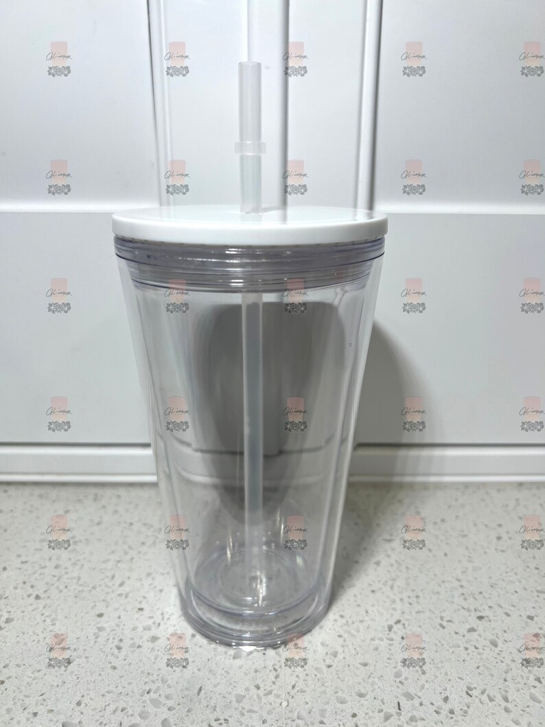 Puede incluir: Un vaso transparente de doble pared con tapa blanca y pajita transparente. El vaso est&aacute; vac&iacute;o, mostrando su dise&ntilde;o transparente. La pajita es recta y encaja en un agujero de la tapa. El vaso est&aacute; dise&ntilde;ado para bebidas fr&iacute;as.