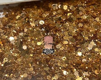 May include: A close-up image of gold glitter. The glitter is a mix of different sizes and shapes, creating a shimmering effect.
